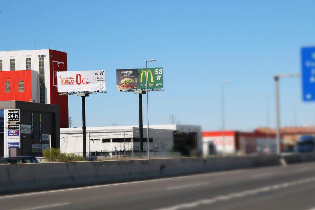 Monopostes publicitarios exteriores de Opel y McDonald's junto a una carretera en España.