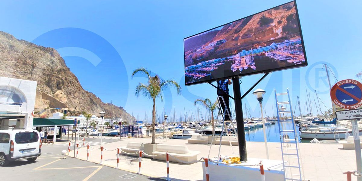 Instalación de una pantalla LED gigante exterior de Cosmi en una zona portuaria concurrida.