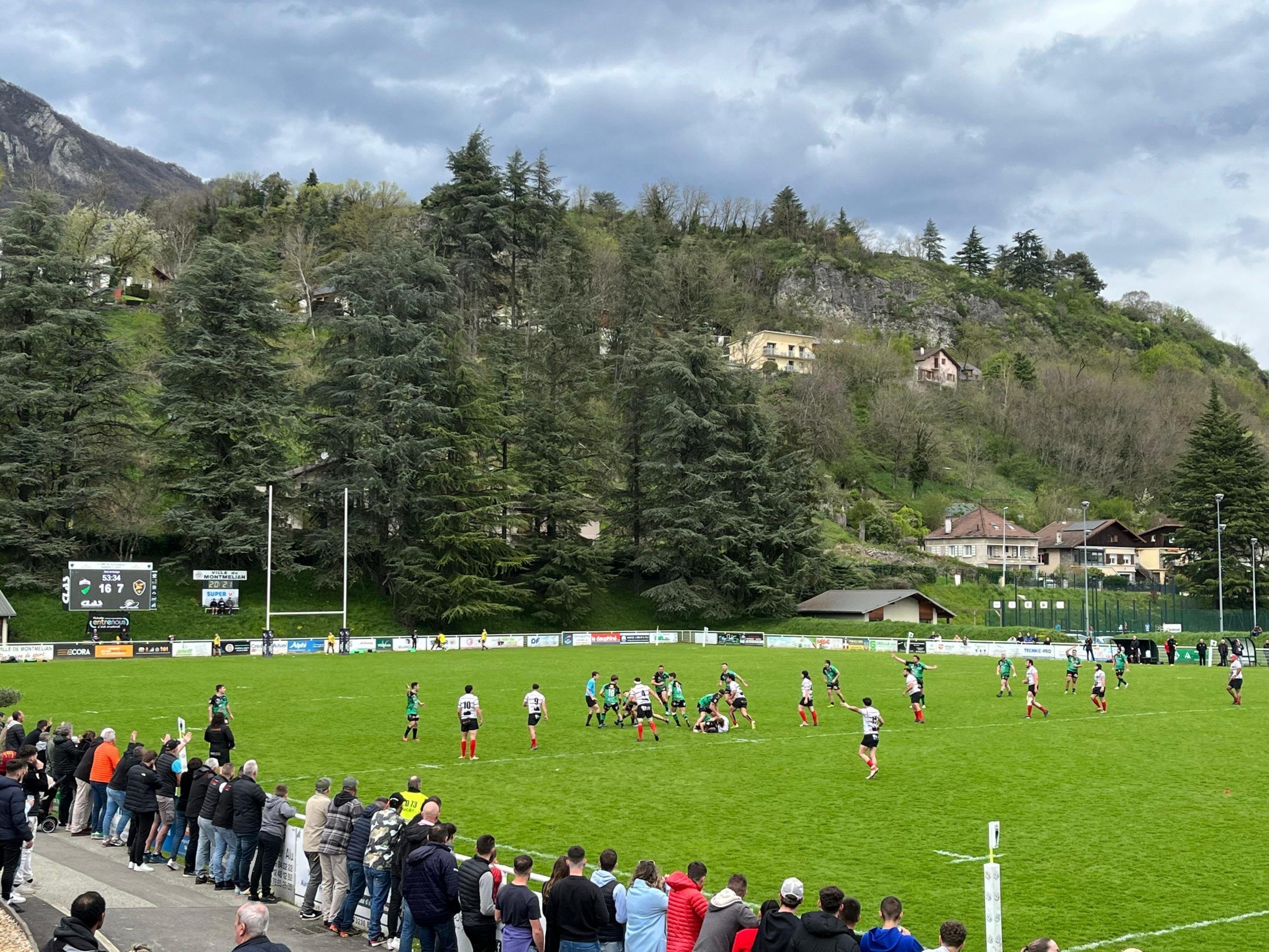 En la imagen se muestran a los equipos de rugby preparados para empezar a jugar y de fondo, coronando el campo de rugby, el magestuoso videomarcador
