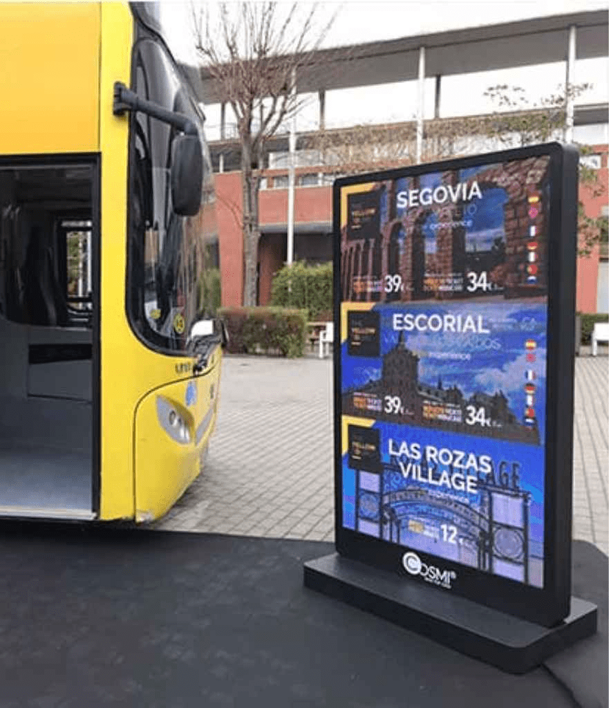 Mupi digital publicitario de Cosmi instalado junto a un autobús en la calle.