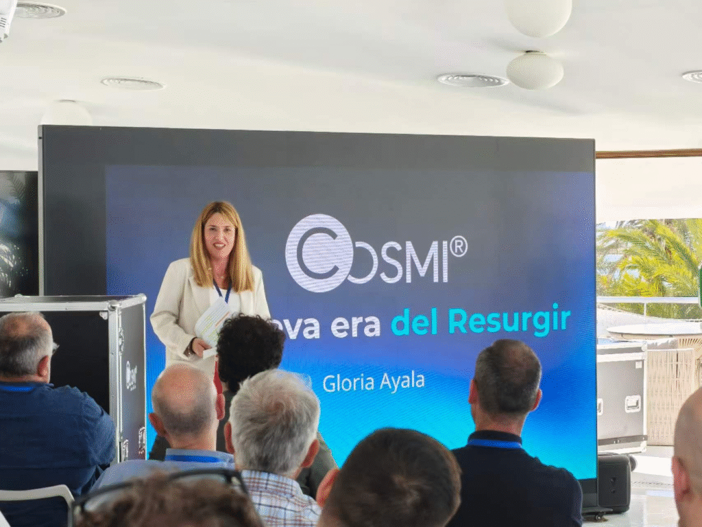 Ponente junto a pantalla LED grande con el logotipo de la nueva era de COSMI.